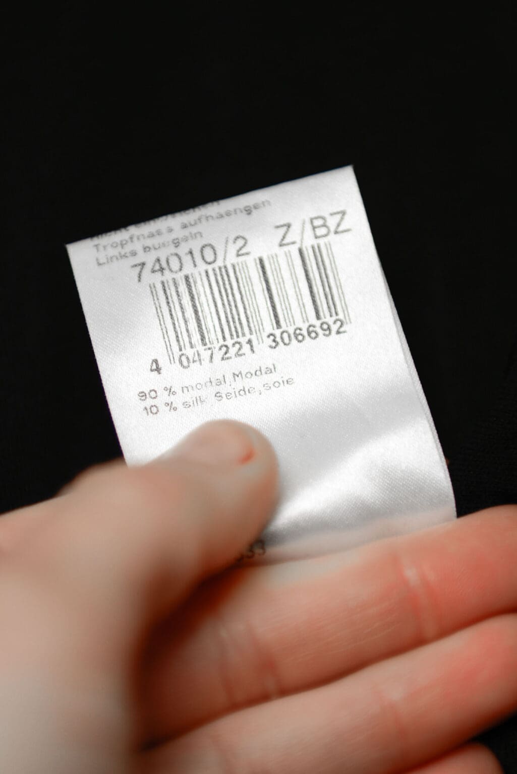 Schwarzes Marc Cain Kleid aus Modal und Seide mit Raffung im Brustbereich, langärmelig, figurbetont geschnitten, auf weißem Hintergrund hängend.