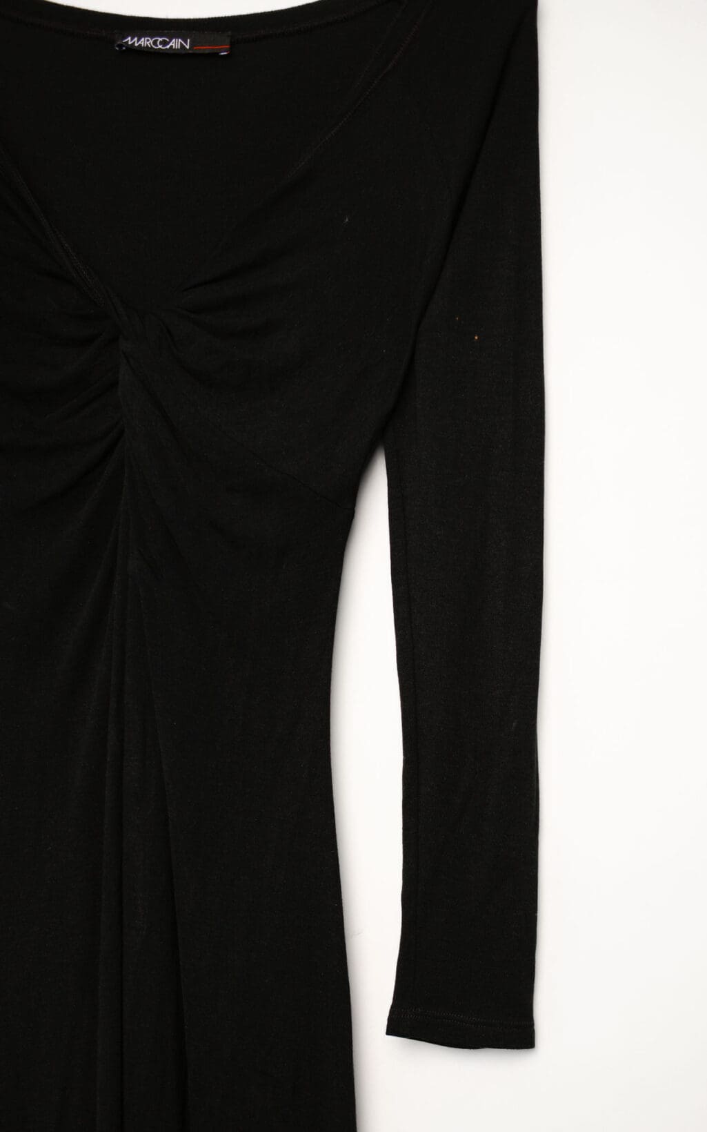 Schwarzes Marc Cain Kleid aus Modal und Seide mit Raffung im Brustbereich, langärmelig, figurbetont geschnitten, auf weißem Hintergrund hängend.