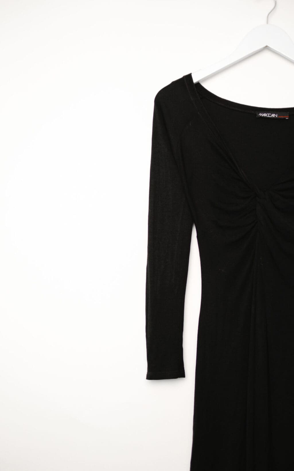 Schwarzes Marc Cain Kleid aus Modal und Seide mit Raffung im Brustbereich, langärmelig, figurbetont geschnitten, auf weißem Hintergrund hängend.