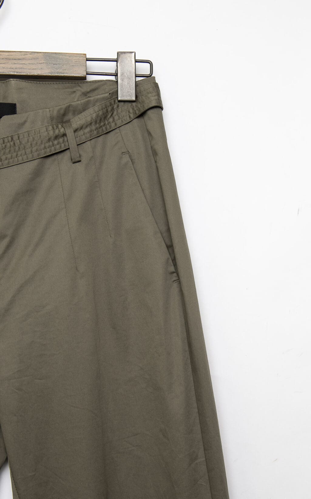 CAMBIO Hose &ndash; Khakihosen der Gr&ouml;&szlig;e 38 werden auf einem h&ouml;lzernen Kleiderb&uuml;gel vor einem wei&szlig;en Hintergrund pr&auml;sentiert, wobei der Hosenbund und die Taschen hervorgehoben werden und nur die obere H&auml;lfte sichtbar ist.