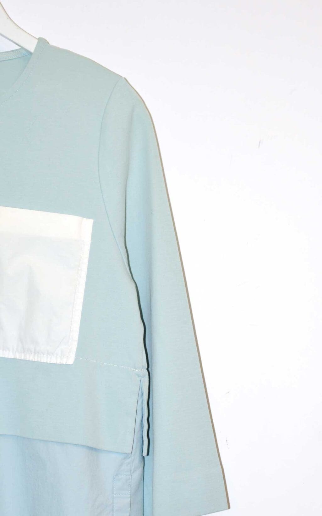 Hellblaues COS Damen-Top mit 3/4-&Auml;rmeln, asymmetrischem Lagen-Look und einer wei&szlig;en aufgesetzten Brusttasche. Hochwertiges Secondhand-Designer-Teil, verf&uuml;gbar auf Monkky.ch.