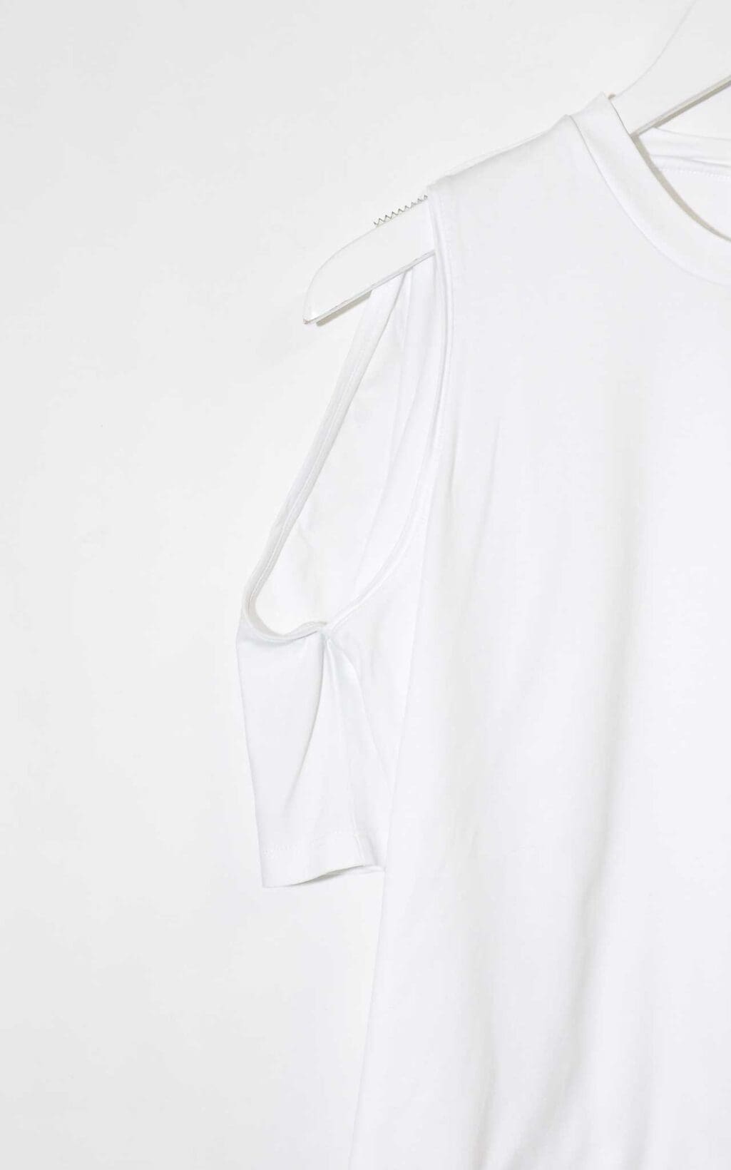 Wei&szlig;es Designer-Shirt von Dion Lee mit Cut-Out-Schultern und Rundhalsausschnitt, auf einem wei&szlig;en Kleiderb&uuml;gel vor hellem Hintergrund pr&auml;sentiert.