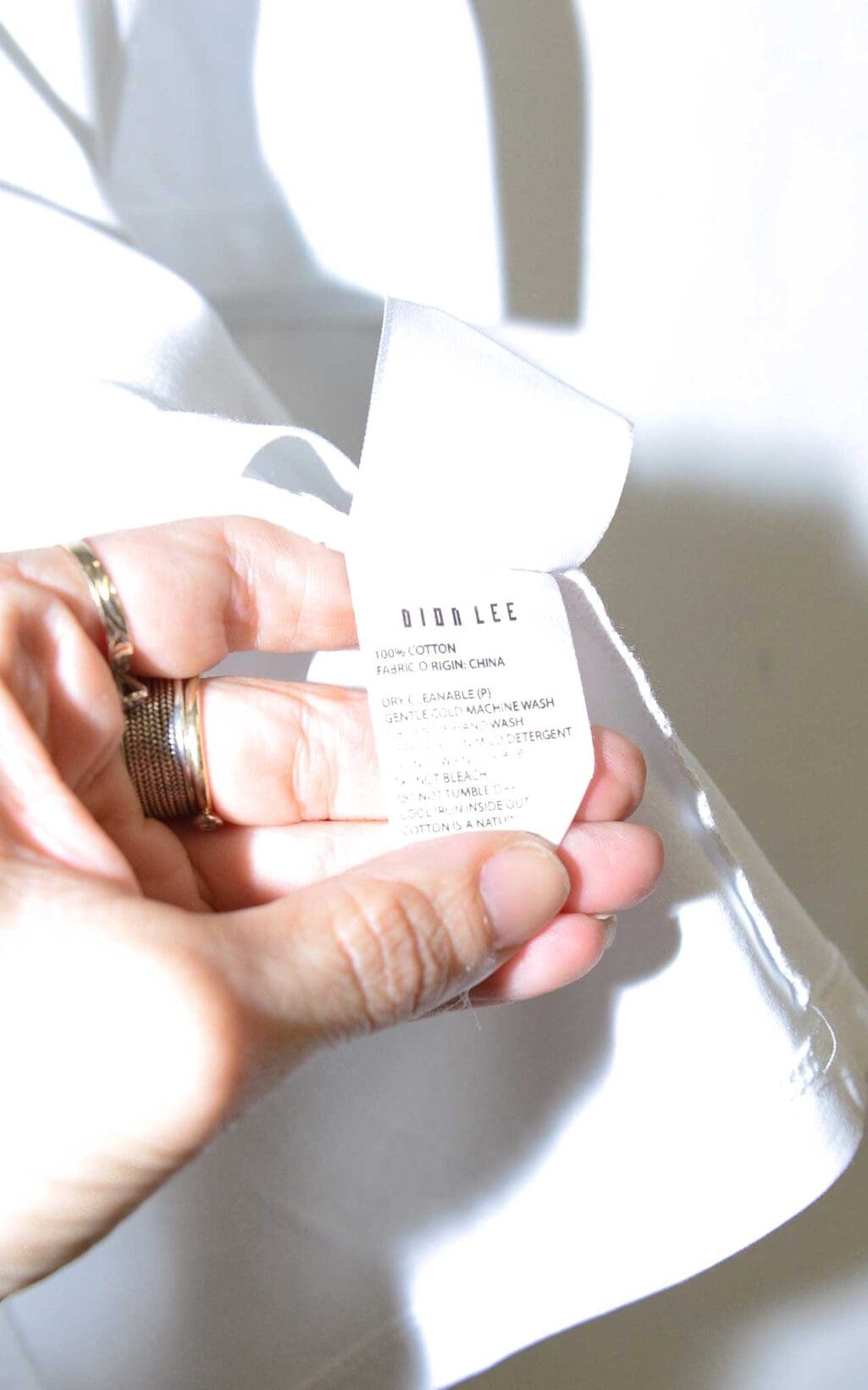 Wei&szlig;es Designer-Shirt von Dion Lee mit Cut-Out-Schultern und Rundhalsausschnitt, auf einem wei&szlig;en Kleiderb&uuml;gel vor hellem Hintergrund pr&auml;sentiert.