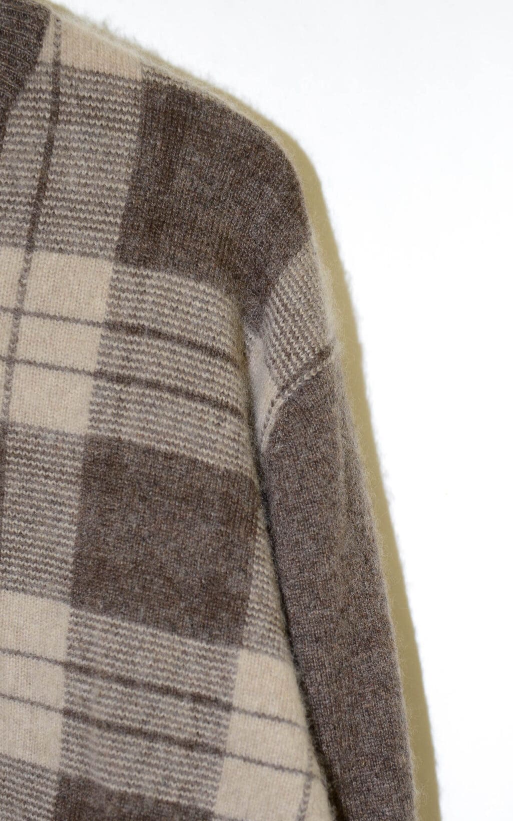 Secondhand Kaschmirpullover mit V-Ausschnitt in Braun- und Beiget&ouml;nen, kariertes Muster, locker geschnitten. H&auml;ngt auf einem wei&szlig;en Kleiderb&uuml;gel, Etikett mit &bdquo;Grant Thomas&ldquo; sichtbar.