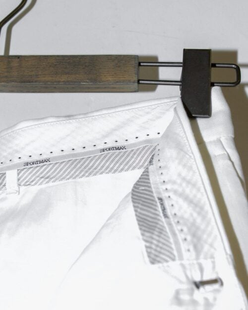 Nahaufnahme der Sportmax Hose - Gr. 36 in Wei&szlig;, h&auml;ngend auf einem Holzb&uuml;gel. Der innere Bund ist mit dem &bdquo;SPORTMAX&ldquo;-Branding und feinen Streifendetails versehen.
