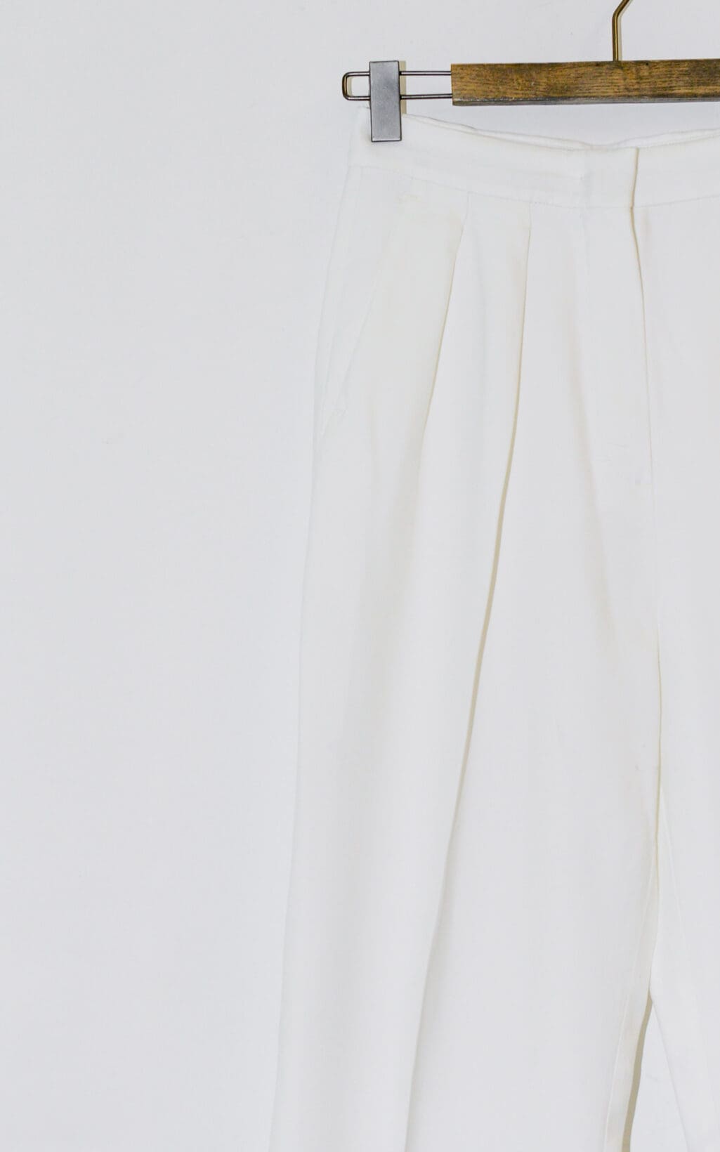 Der obere Teil der Sportmax Hose &ndash; Gr. 36, einer wei&szlig;en Hose mit hoher Taille und B&uuml;gelfalten, h&auml;ngt auf einem h&ouml;lzernen Kleiderb&uuml;gel vor einem schlichten wei&szlig;en Hintergrund.