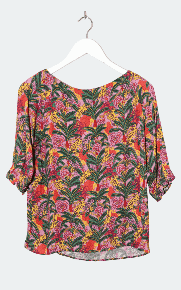 Das Balzac-Top – Gr. 40 hängt auf einem weißen Kleiderbügel und zeigt gerüschte Halbärmel und ein lebhaftes Muster aus gelben Tigern, grünen Blättern und rosa Blumen auf rotem Hintergrund.