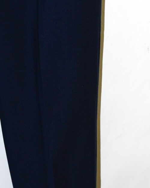 Eine Nahaufnahme der Closed Auckley Hose &ndash; W26, einer dunklen Hose, die an einer wei&szlig;en Wand h&auml;ngt und bei der nur ein Teil eines Hosenbeins sichtbar ist.