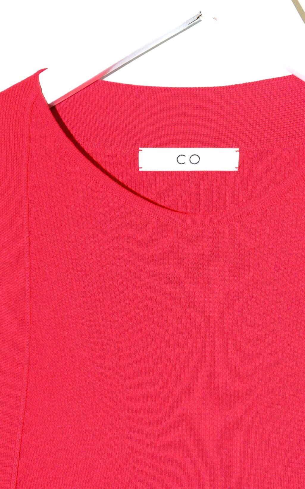 &Auml;rmelloses rotes Top von CO aus feinem Seidenstrick, schlicht geschnitten, auf einem wei&szlig;en Kleiderb&uuml;gel vor hellem Hintergrund pr&auml;sentiert.