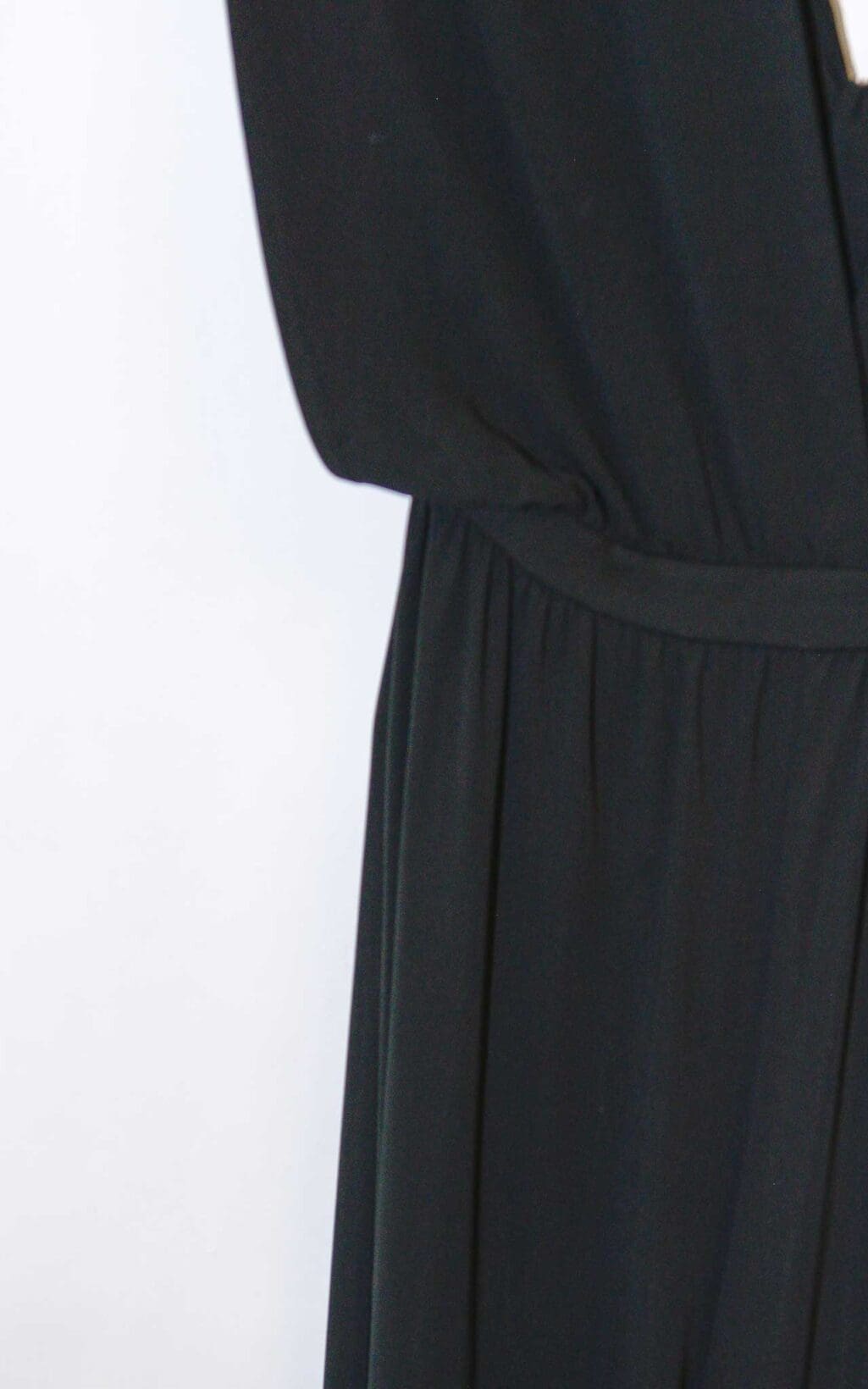 Eleganter schwarzer Jumpsuit von Michael Kors Collection mit tiefem V-Ausschnitt und weitem Bein, &auml;rmellos, auf einem wei&szlig;en Kleiderb&uuml;gel vor hellem Hintergrund pr&auml;sentiert.