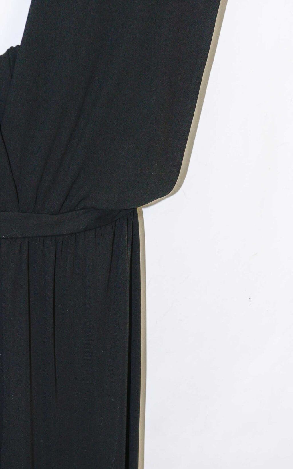 Eleganter schwarzer Jumpsuit von Michael Kors Collection mit tiefem V-Ausschnitt und weitem Bein, &auml;rmellos, auf einem wei&szlig;en Kleiderb&uuml;gel vor hellem Hintergrund pr&auml;sentiert.