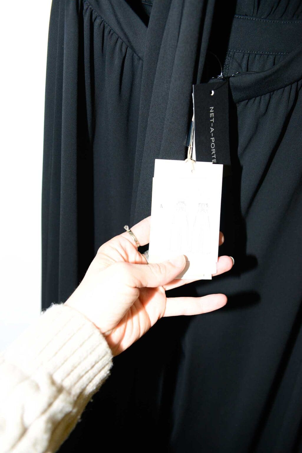 Eleganter schwarzer Jumpsuit von Michael Kors Collection mit tiefem V-Ausschnitt und weitem Bein, &auml;rmellos, auf einem wei&szlig;en Kleiderb&uuml;gel vor hellem Hintergrund pr&auml;sentiert.