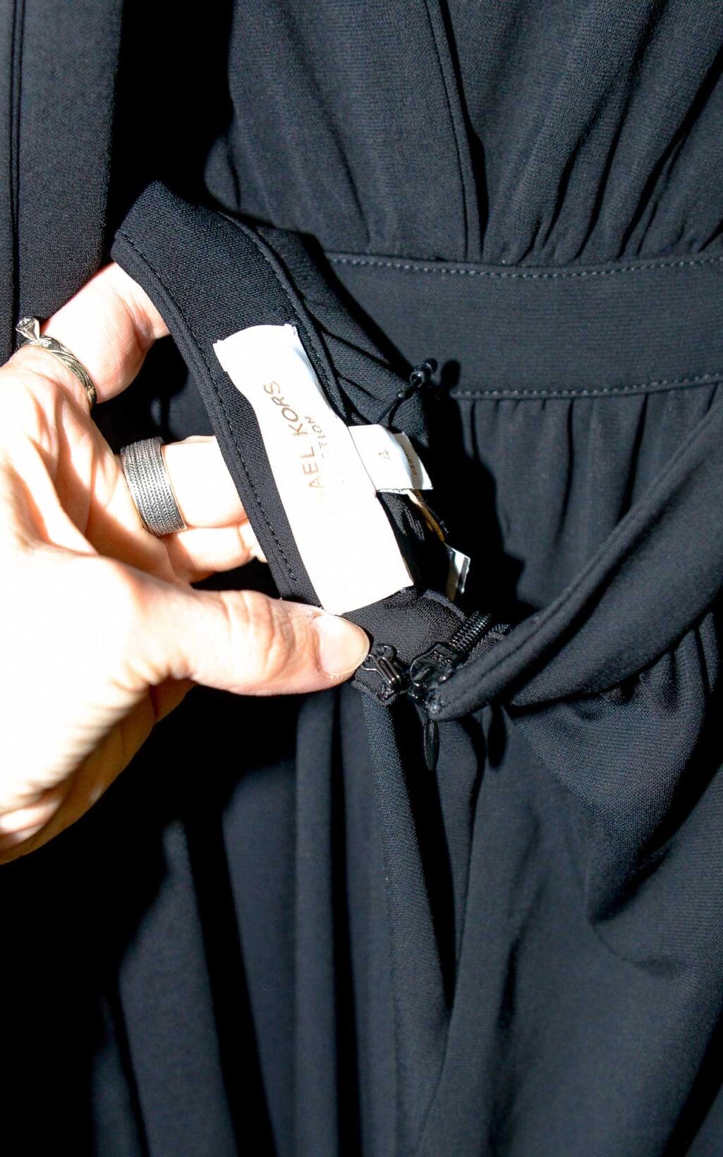 Eleganter schwarzer Jumpsuit von Michael Kors Collection mit tiefem V-Ausschnitt und weitem Bein, &auml;rmellos, auf einem wei&szlig;en Kleiderb&uuml;gel vor hellem Hintergrund pr&auml;sentiert.