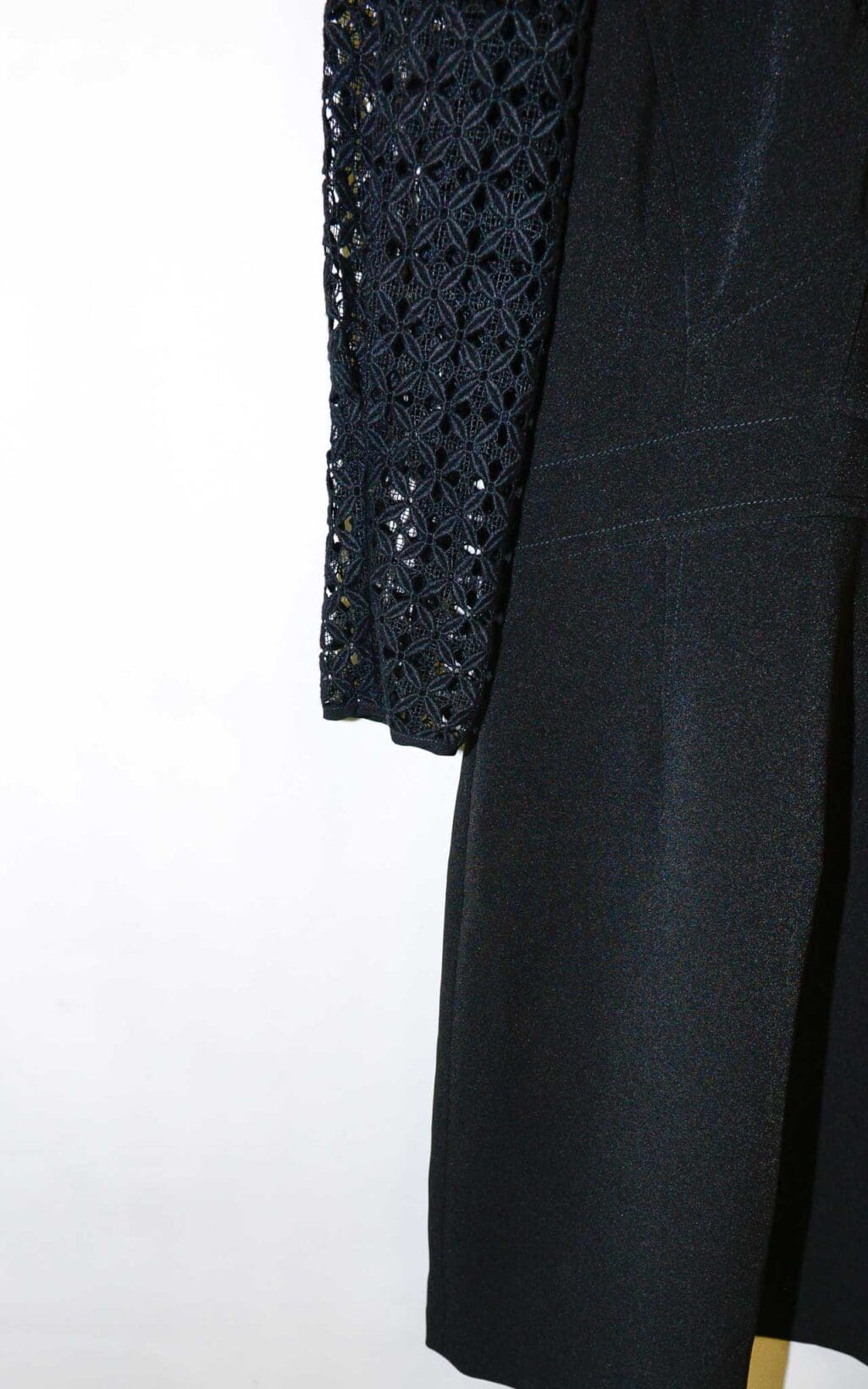 Schwarzes Secondhand Kleid von Sandro mit Spitzenoberteil, 3/4-&Auml;rmeln und tailliertem Schnitt, auf einem wei&szlig;en Kleiderb&uuml;gel vor hellem Hintergrund pr&auml;sentiert.