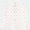 Deen & Keenu Bluse – Div. Grössen: Weiße Langarmbluse mit Stehkragen und orangen Fruchtprints, abgebildet auf einem Kleiderbügel vor hellem Hintergrund.