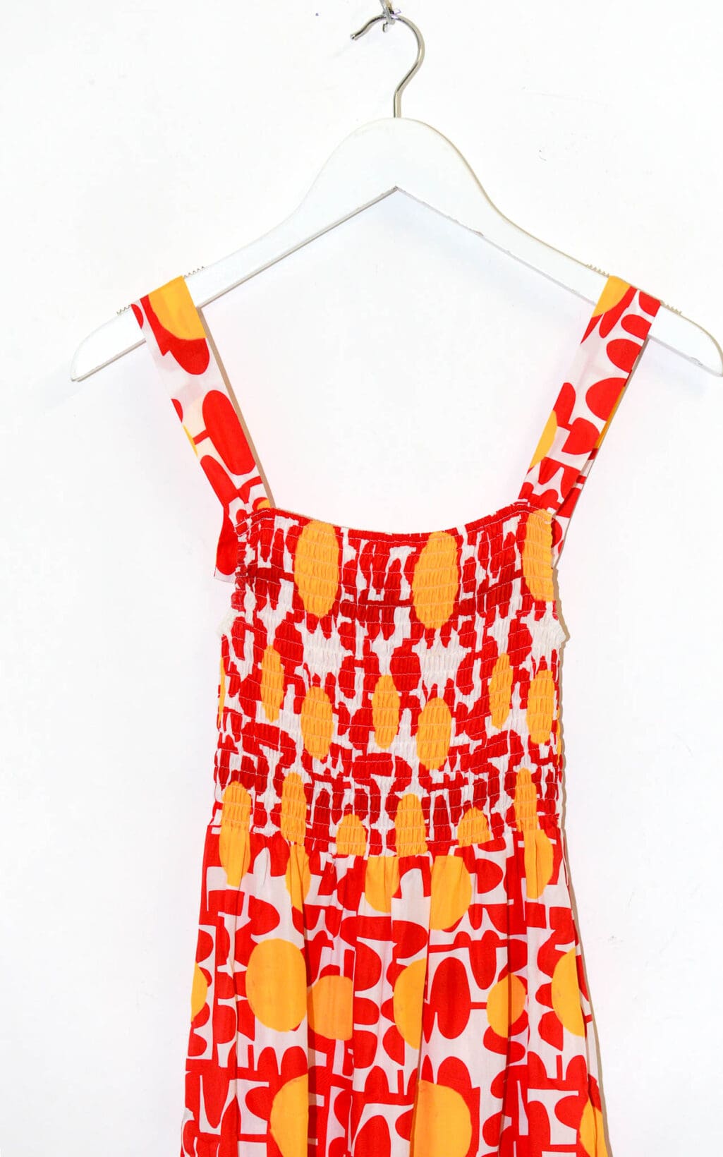 Das Maxikleid (Gr. 40) von Elise Chalmin Paris ist ein &auml;rmelloses Kleid mit breiten Tr&auml;gern, einem abstrakten Blumenmuster in Rot und Gelb und einem gerafften, dehnbaren Oberteil, das auf einem wei&szlig;en Kleiderb&uuml;gel vor wei&szlig;em Hintergrund pr&auml;sentiert wird.