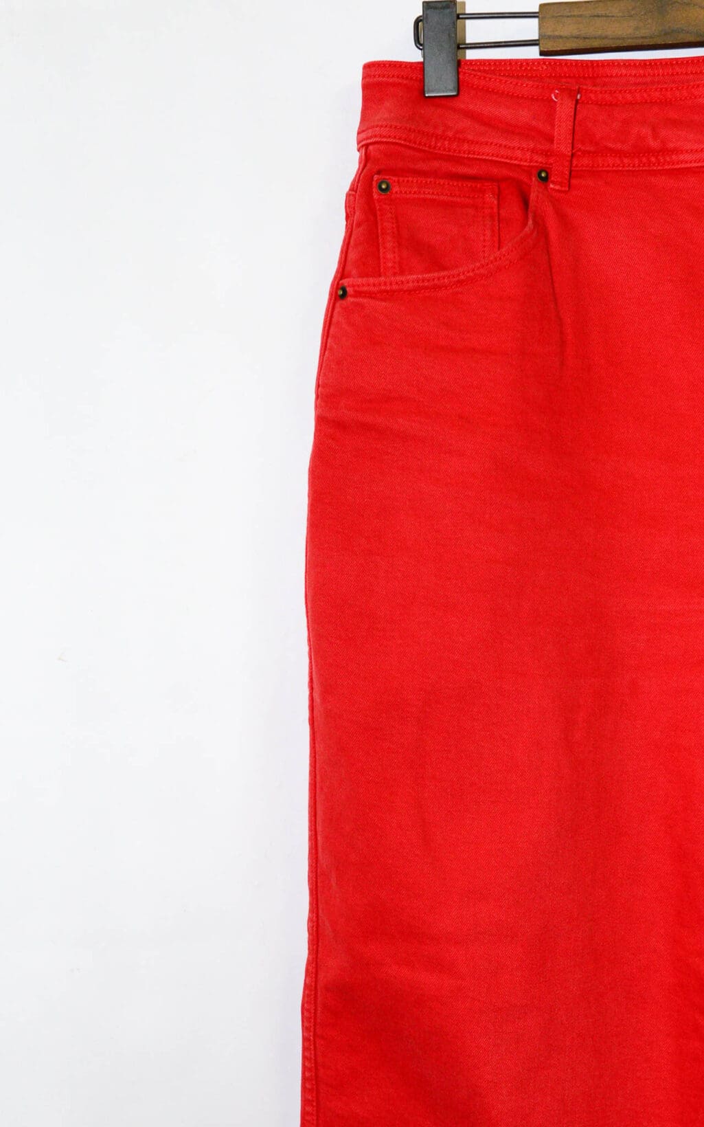 Eine S&eacute;zane Wideleg Jeans in Gr&ouml;&szlig;e 44 h&auml;ngt auf einem dunklen Holzb&uuml;gel und ist von der Taille bis zur Mitte des Oberschenkels vor einem schlichten wei&szlig;en Hintergrund zu sehen. Nur die linke Seite der Jeans ist sichtbar.