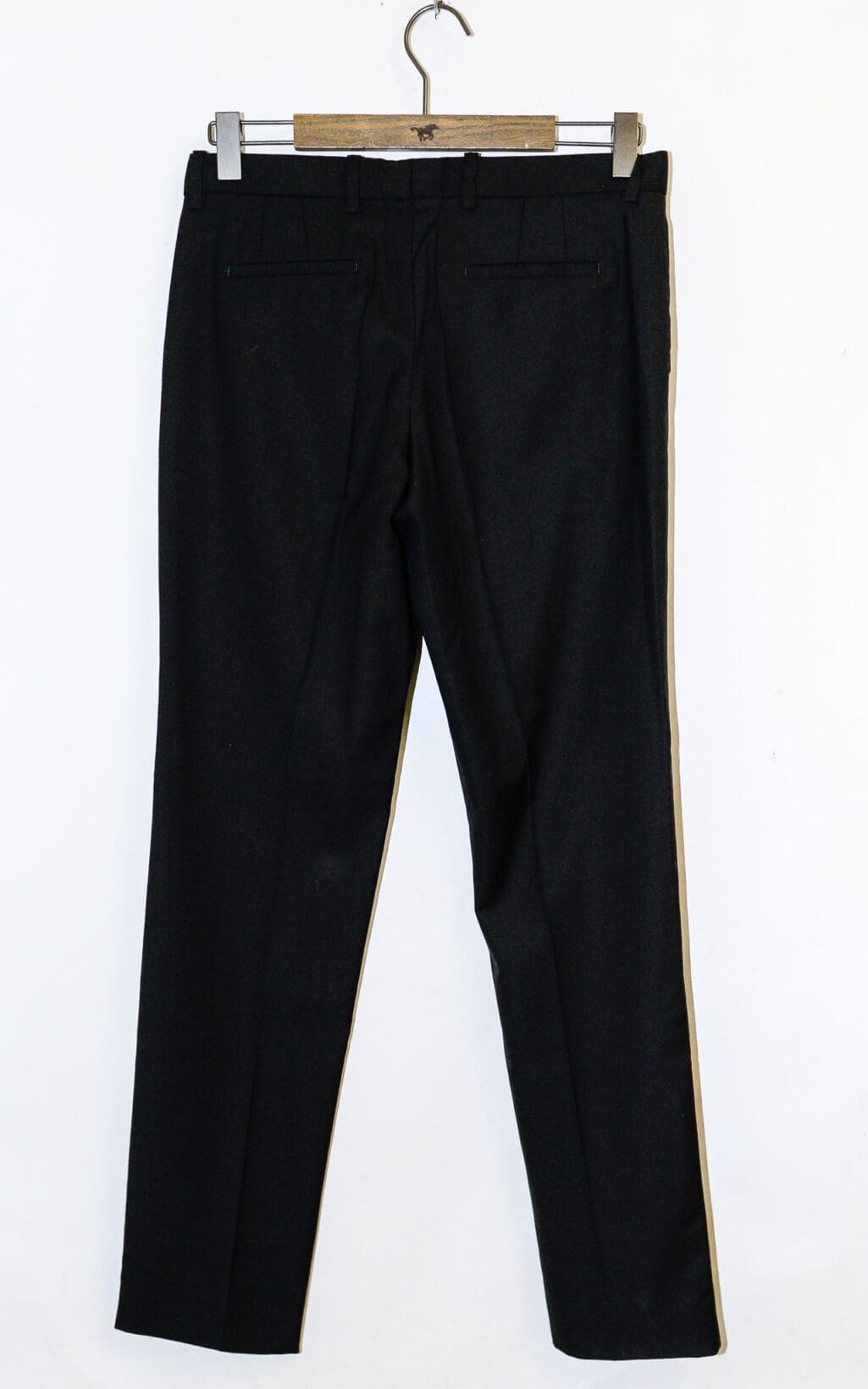 Die JOSEPH 100% Wolle Chino Hose in Gr&ouml;&szlig;e 38 h&auml;ngt auf einem h&ouml;lzernen Kleiderb&uuml;gel vor einem wei&szlig;en Hintergrund, von hinten betrachtet, mit zwei sichtbaren Leistentaschen und G&uuml;rtelschlaufen.