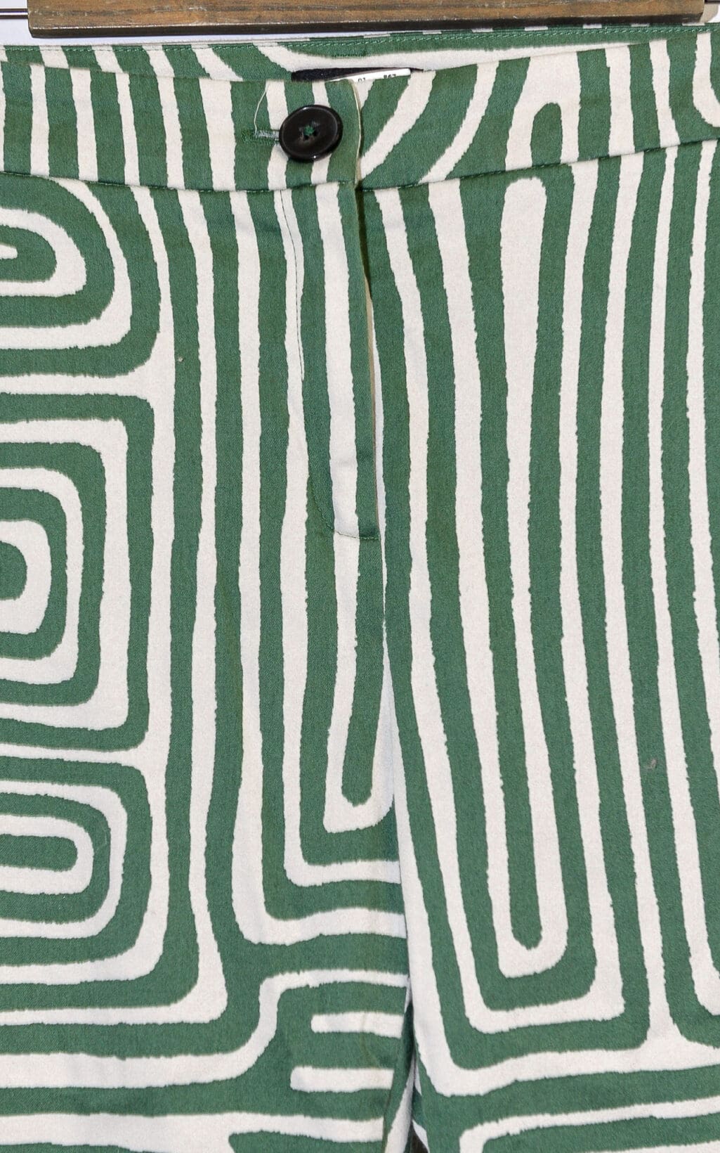 Nahaufnahme der EMME Marella Hose &ndash; Gr. 40 mit einem kr&auml;ftigen gr&uuml;n-wei&szlig;en labyrinthartigen geometrischen Muster, einem schwarzen Knopf und einem Rei&szlig;verschluss am Hosenbund.