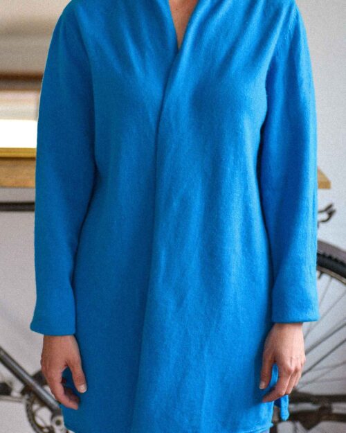 Eine Person tr&auml;gt eine Steffen Schraut Strickjacke (Gr&ouml;&szlig;e 40) in Hellblau, lang&auml;rmelig und kragenlos. In einem Innenraum ist nur der Oberk&ouml;rper zu sehen, im Hintergrund sind ein Teil eines Fahrrads und Wohnm&ouml;bel zu sehen.