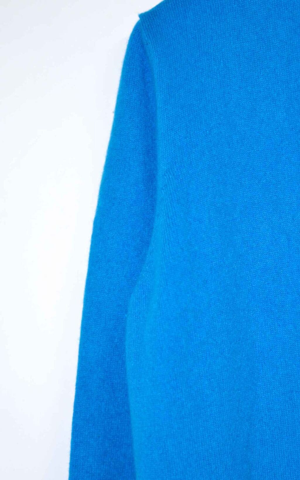 Eine Nahaufnahme der Steffen Schraut Strickjacke aus 100% Kaschmir (Gr. 40) in leuchtendem Blau, wobei die Details an &Auml;rmeln und Schultern vor wei&szlig;em Hintergrund hervorgehoben werden.