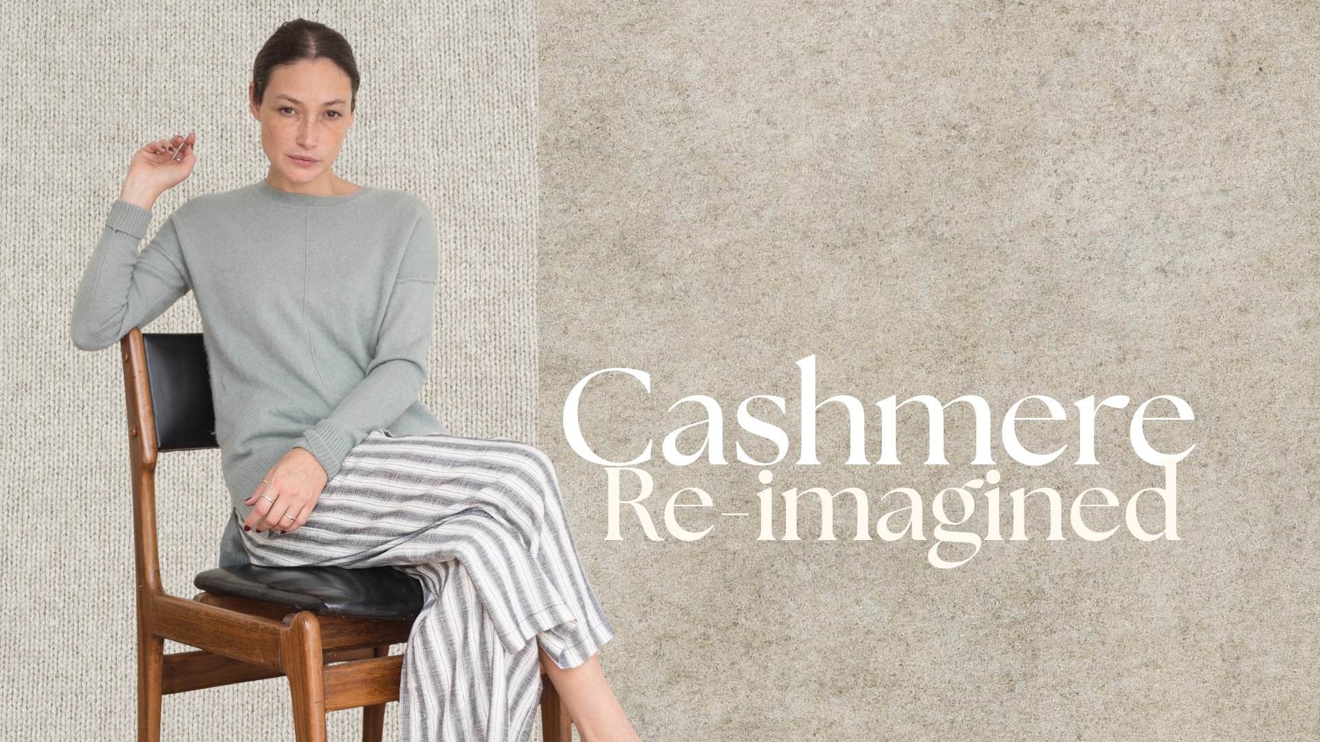 Frau sitzt auf einem Holzstuhl und trägt einen hellgrünen Cashmerepullover und gestreifte Hose, vor einem warmen, naturfarbenen Texturhintergrund. Rechts steht der Schriftzug „Cashmere Re-imagined“.
