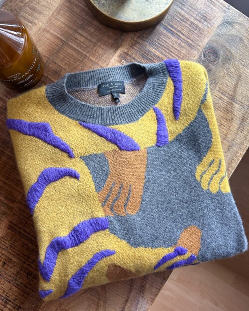 Rag&Bone Cashmere Pullover mit Tiger zusammengefaltet auf Holztisch.