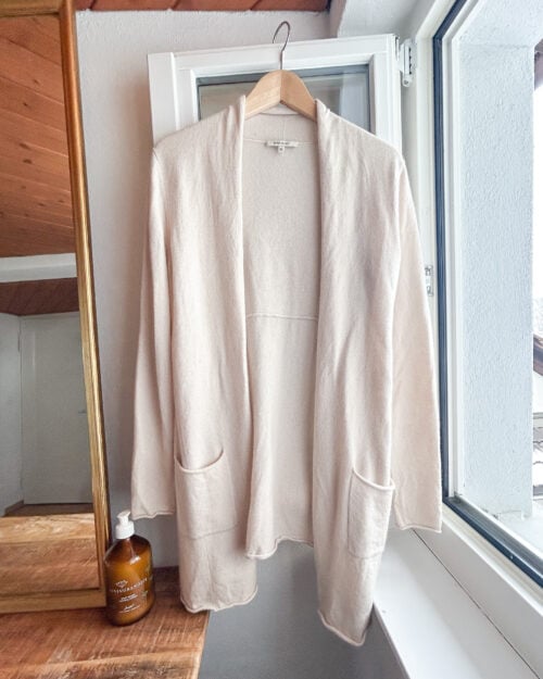 Rena Marx Kaschmir Cardigan in Ecru. Secondhand. Aufgeh&auml;ngt an Kleiderb&uuml;gel.