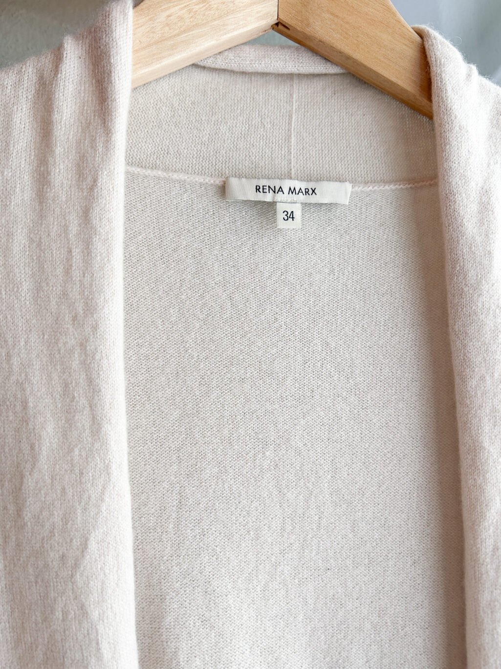 Rena Marx Kaschmir Cardigan in Ecru. Secondhand. Gefaltet auf Holztisch.