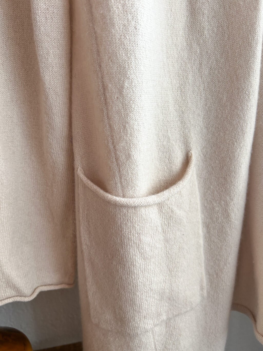 Rena Marx Kaschmir Cardigan in Ecru. Secondhand. Gefaltet auf Holztisch.