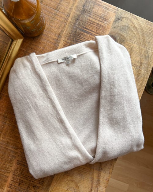 Rena Marx Kaschmir Cardigan in Ecru. Secondhand. Gefaltet auf Holztisch.