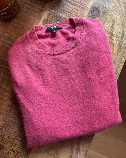 uniqlo cashmere rosa-1 Rosaroter gefalteter Uniqlo Cashmere Pullover auf Tisch. Secondhand.