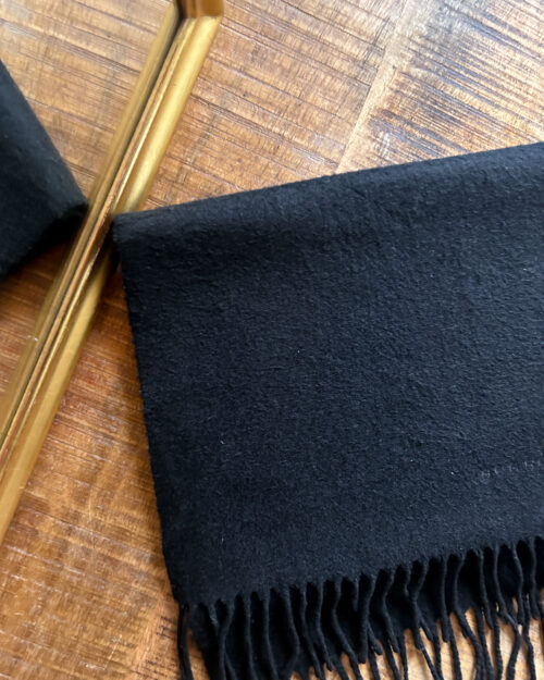 Schwarzer Secondhand Kaschmir Schal von Burberry gefaltet auf Holztisch.