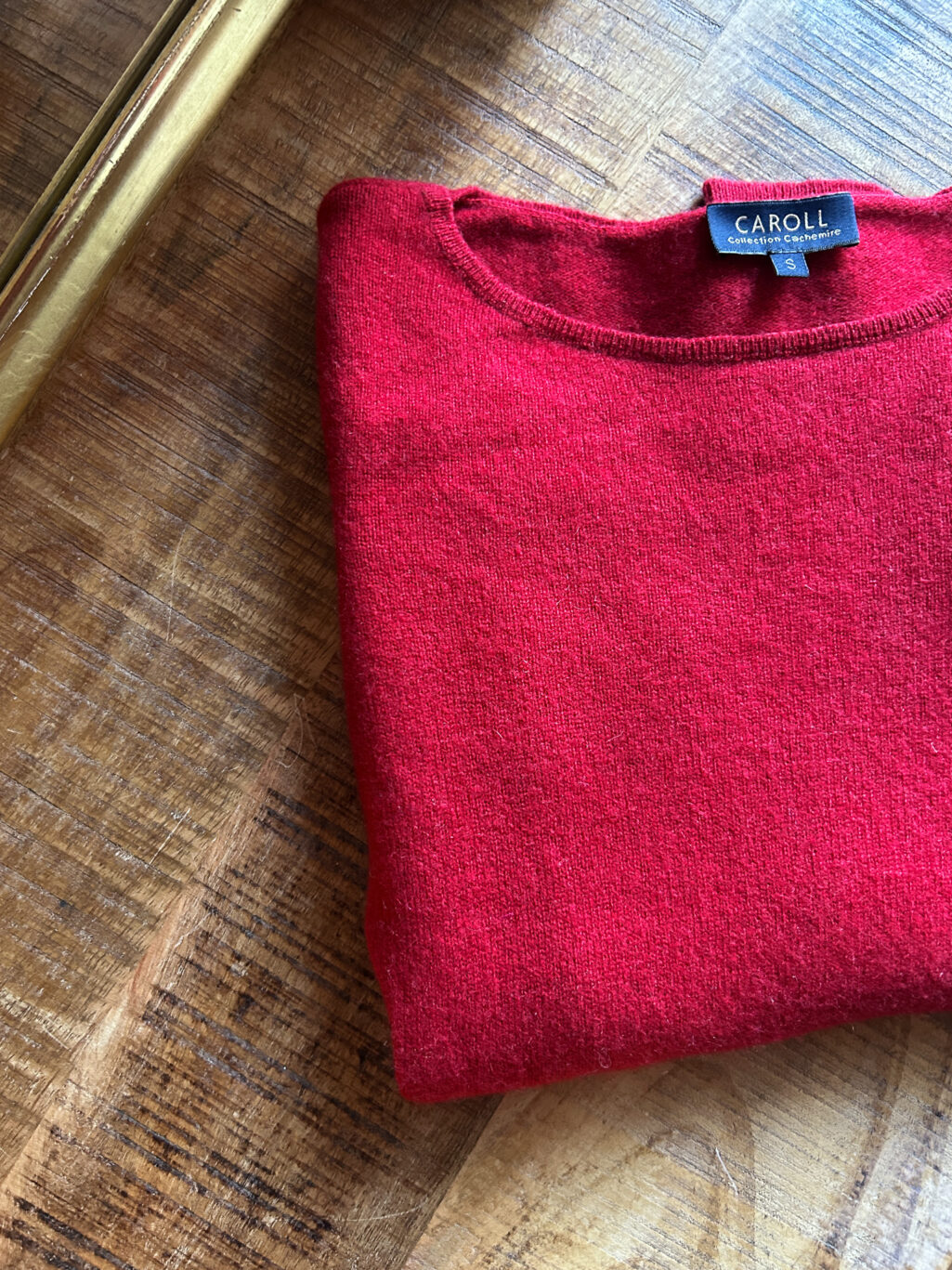 Secondhand Cashmere Pullover in Rot von Caroll. Zusammengefaltet auf Holztisch.
