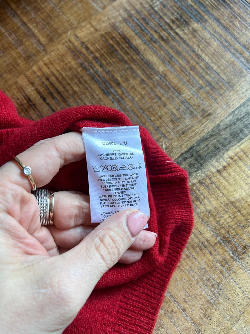 Secondhand Cashmere Pullover in Rot von Caroll. Zusammengefaltet auf Holztisch.