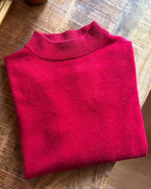 Monkky Cashmere Pullover mit hohem Kragen in Himbeerrot. Preloved. Gefaltet auf Holztisch.