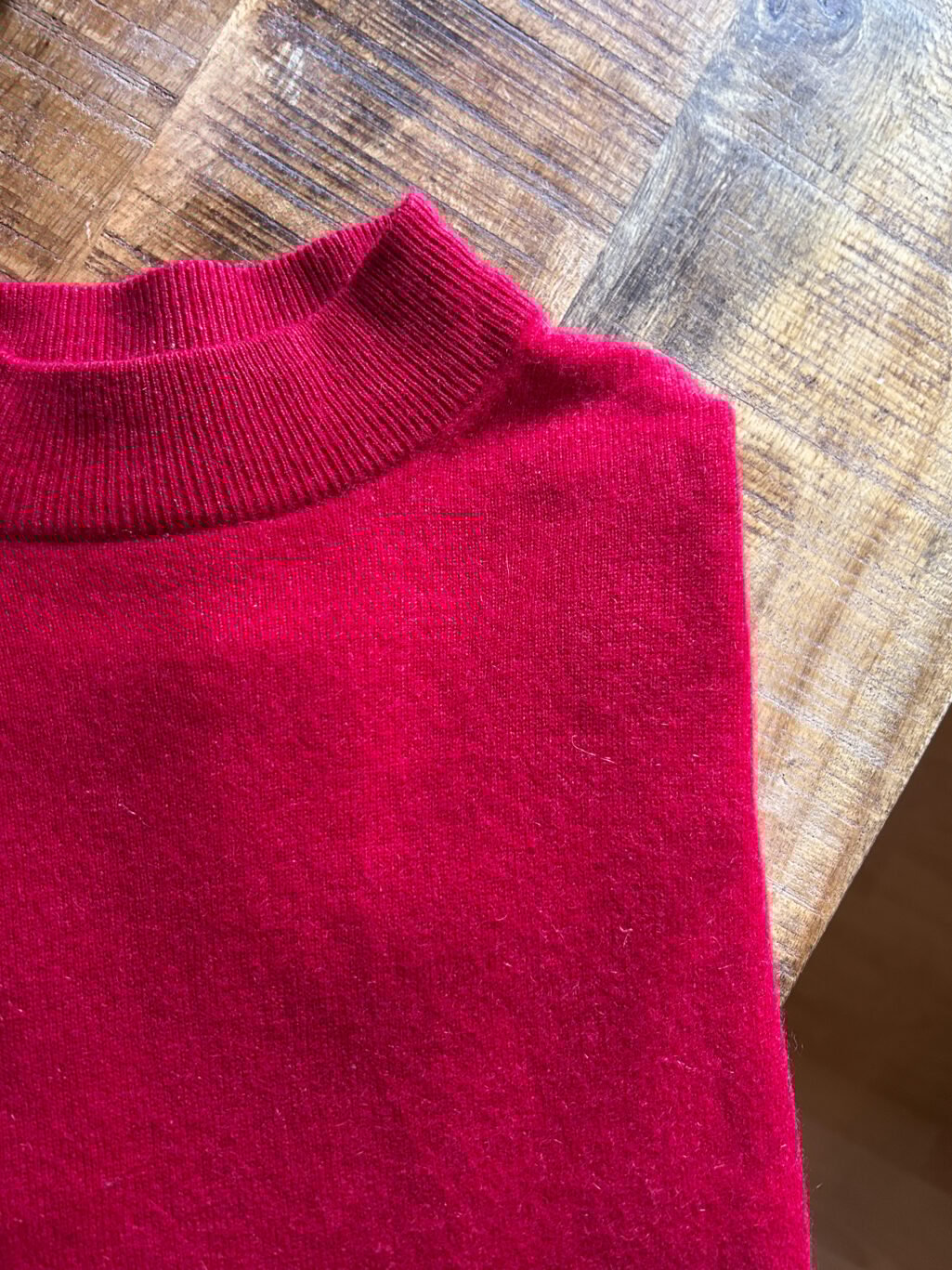 Monkky Cashmere Pullover mit hohem Kragen in Himbeerrot. Preloved. Gefaltet auf Holztisch.