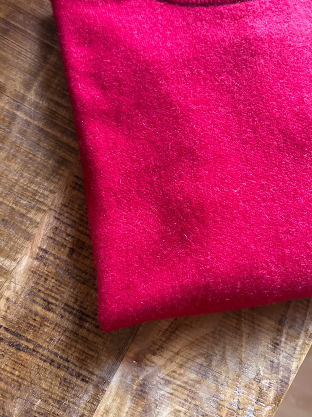 Monkky Cashmere Pullover mit hohem Kragen in Himbeerrot. Preloved. Gefaltet auf Holztisch.