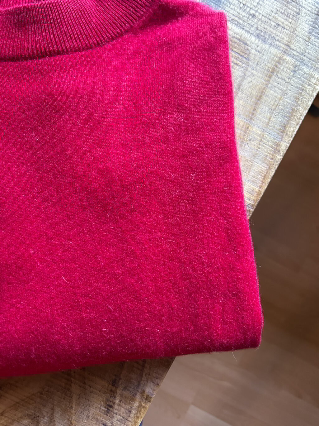 Monkky Cashmere Pullover mit hohem Kragen in Himbeerrot. Preloved. Gefaltet auf Holztisch.