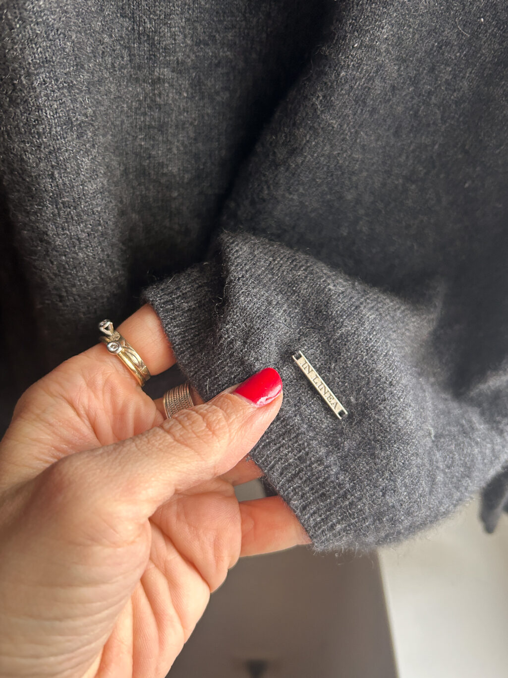 In Linea Firenze grauer preloved Cashmere Pullover mit V-Neck, gefaltet auf Holztisch.