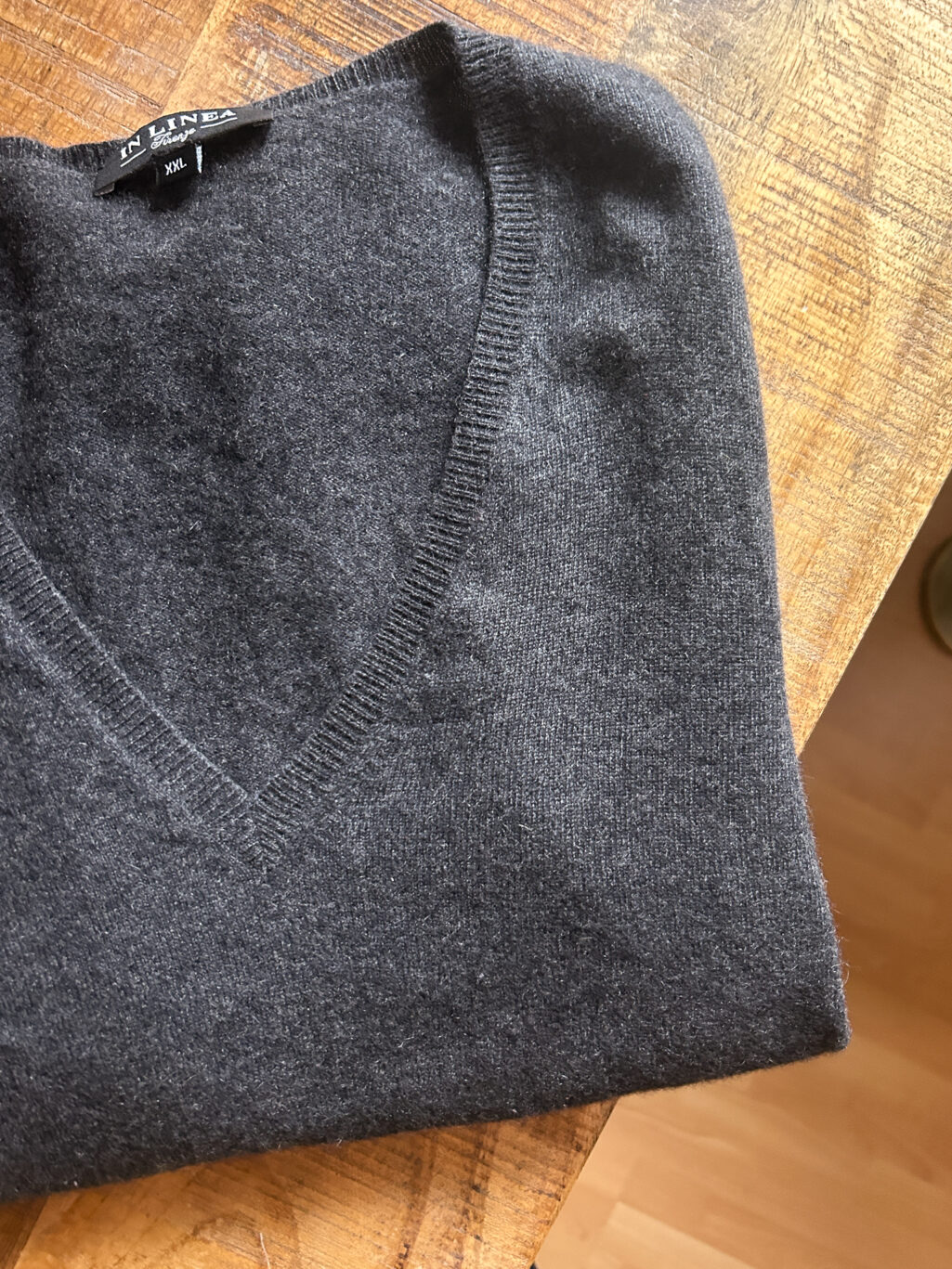 In Linea Firenze grauer preloved Cashmere Pullover mit V-Neck, gefaltet auf Holztisch.
