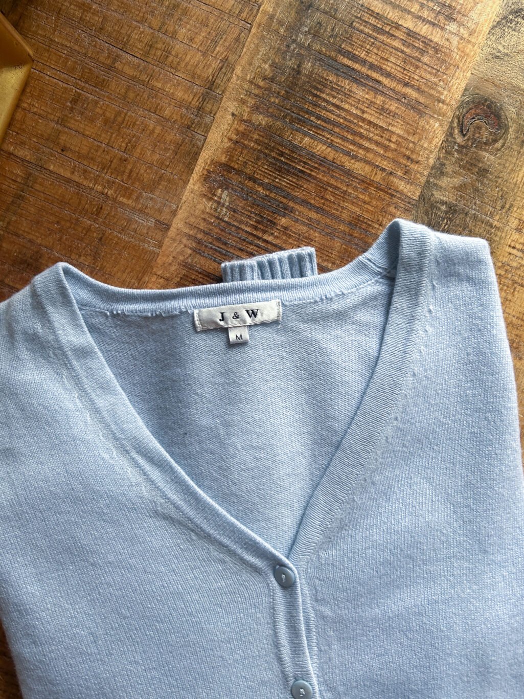 J&W Cashmere Cardigan in Hellblau mit Kn&ouml;pfen und V-Ausschnitt. Preloved, gefaltet auf Holztisch.