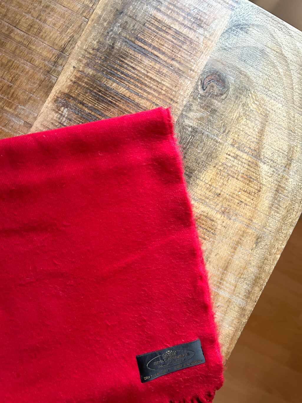 Monkky preloved Kaschmir Schal in Rot. Handgefertigt in Deutschland, gefaltet auf Holztisch.