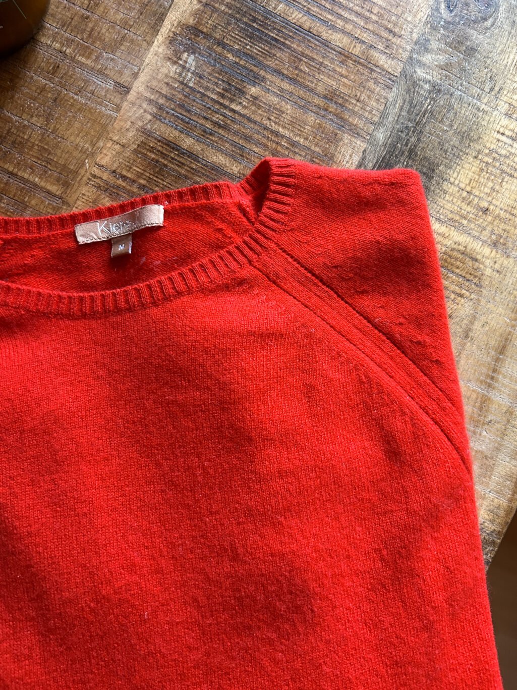 Kier&J Cashmere Pullover, preloved in Rot Orange. Gefaltete auf Holztisch.