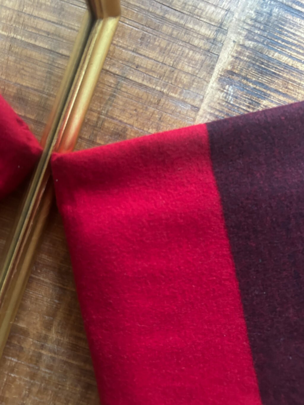 Grosser Kaschmir Schal von Michael Kors preloved und modern. Zweifarbig in Rot und Bordeaux, gefaltet auf Holztisch.