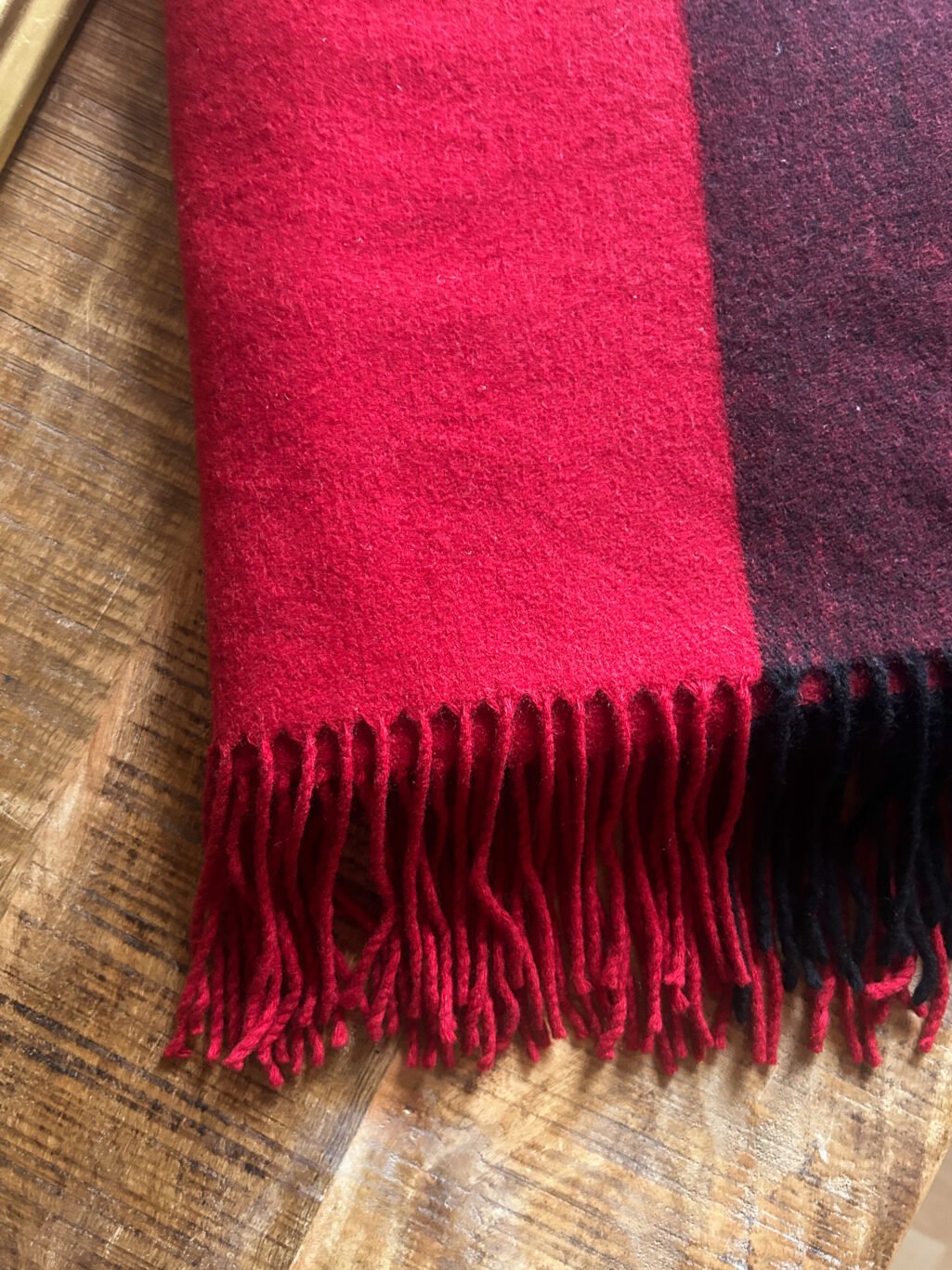 Grosser Kaschmir Schal von Michael Kors preloved und modern. Zweifarbig in Rot und Bordeaux, gefaltet auf Holztisch.