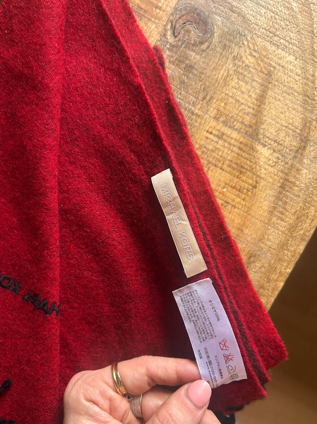 Grosser Kaschmir Schal von Michael Kors preloved und modern. Zweifarbig in Rot und Bordeaux, gefaltet auf Holztisch.