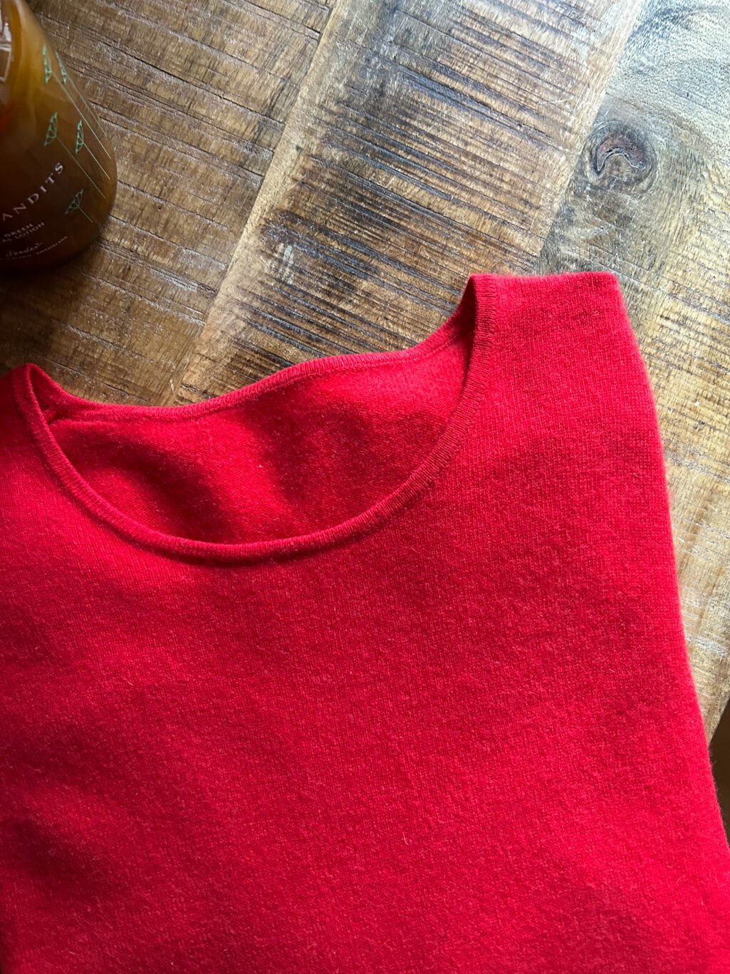 Roter Kaschmir Pullover mit Rundhals-Ausschnitt von Monkky. Preloved und modern. Gefaltet auf Holztisch.