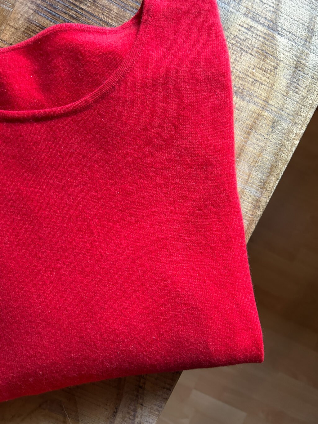 Roter Kaschmir Pullover mit Rundhals-Ausschnitt von Monkky. Preloved und modern. Gefaltet auf Holztisch.