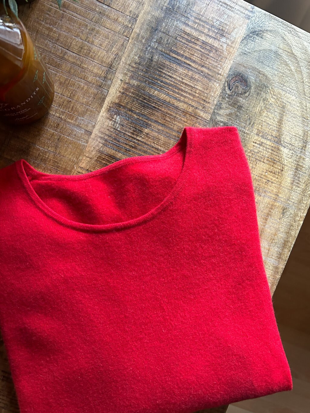 Roter Kaschmir Pullover mit Rundhals-Ausschnitt von Monkky. Preloved und modern. Gefaltet auf Holztisch.